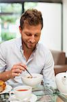 Souriant petit-déjeuner homme manger à table