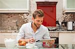 Smiling man reading at breakfast