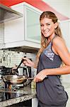 Smiling woman cooking in kitchen