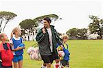 Coach carrying soccer balls on pitch