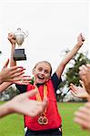 Children cheering teammate with trophy