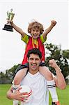Coach carrying child with trophy