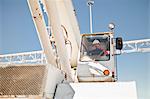 Worker operating crane at oil refinery