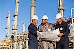 Workers with blueprints at oil refinery