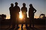 Silhouette of workers at oil refinery