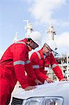 Workers with blueprints at oil refinery