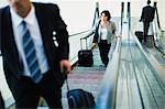 Business people riding escalator