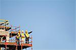 Workers standing on scaffolding on site