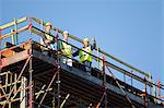 Workers standing on scaffolding on site