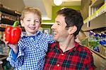 Grocer holding son with bell pepper