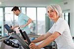 Older woman using treadmill in gym