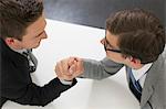 Businessmen arm wrestling in office