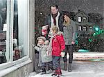 Family admiring Christmas window in snow