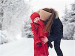 Mutter und Tochter küssen im Schnee