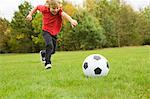 Garçon jouant avec le ballon de soccer dans le champ