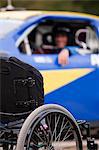 Wheelchair in front of stock car modified for disability racing