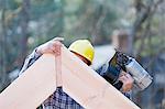 Carpenter nailing a rafter at peak