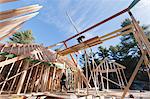 Carpenter lifting rafter into place on upper roof