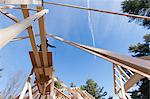 Low angle view of a carpenter stretching hose to reach roof peak