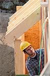 Carpenter reviewing exterior framing of a house