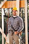 Portrait of a carpenter holding a level on house framing