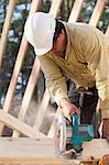 Carpenter using a circular saw on stud