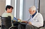 Doctor with muscular dystrophy in wheelchair checking the blood pressure of a patient