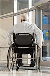 Médecin avec dystrophie musculaire en fauteuil roulant à l'entrée de l'hôpital
