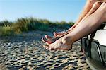 Mid adult couple sitting barefoot on car on beach