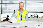 Portrait of an engineer at desk of blueprints in office