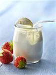 Open yoghurt in a glass pot and strawberries