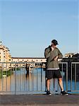 Italy, Florence, Man checking pulse on bridge over River Arno