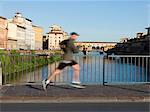 Italy, Florence, Man jogging past Ponte Vecchio over River Arno