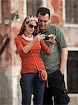 Italy, Venice, Couple viewing digital camera in city