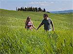 Italy, Tuscany, Couple walking on meadow