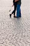 Italy, Rome, Vatican City, Close up of legs of couple with rose standing on cobblestone