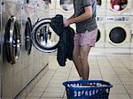 Mann auszuziehen Kleider zu einem Waschsalon