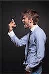 Angry business man screaming on phone over black background
