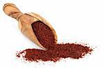 Chili pepper spice powder in an olive wood scoop and scattered over white background.