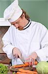 Young chef with carrot, preparing lunch in kitchen