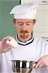 Young chef add salt in the pot, preparing lunch