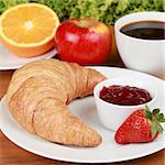 Healthy breakfast with a croissant and strawberry jam. Served with coffee, orange juice, an apple and a muffin.