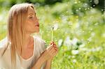 girl blowing on a dandelion lying on the grass