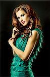 pretty brunette wearing green fashion dress on black background