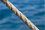 Stretched tight thick rope against blue sea water
