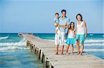 Family of four on wooden jetty by the ocean
