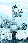 Oil industry. Wellhead with valve armature on a sky background. Toned.