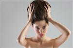 close up portrait of young beautiful girl holding her updo hair posing on grey background
