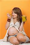 Caucasian pregnant woman sitting on the floor eating pickles