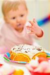 Closeup on birthday cake and eat smeared baby in background|anonymous